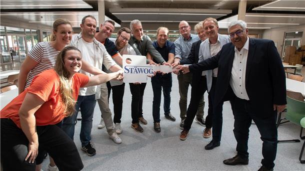 Gruppe lachender Menschen hält STÄWOG-Schlüssel fest