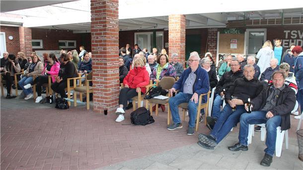 Zahlreiche Bürgerinnen und Bürger sitzen bei einer Bürgerversammlung unter dem überdachten Außenbereich des TSV Wehdel, aufmerksam dem Geschehen folgend.