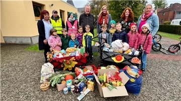 Kinder der St.-Willehad-Kita mit Erwachsenen vor gespendeten Lebensmitteln zum Erntedankfest