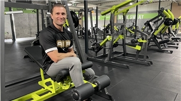 Mann sitzt auf einem Fitnessgerät in einem Studio.