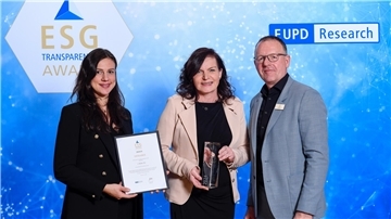 Zwei Frauen und ein Mann mit Urkunde und einem Award.
