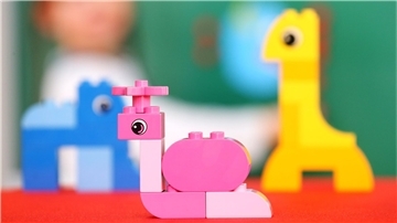 Im Vordergrund ist Kleinkind-Spielzeug von Lego zu sehen, dahinter unscharf ein Kind.