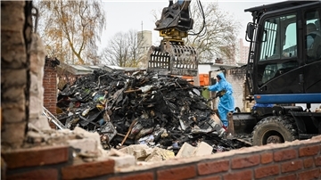 Ruine, Bagger, Arbeiter im Schutzanzug.