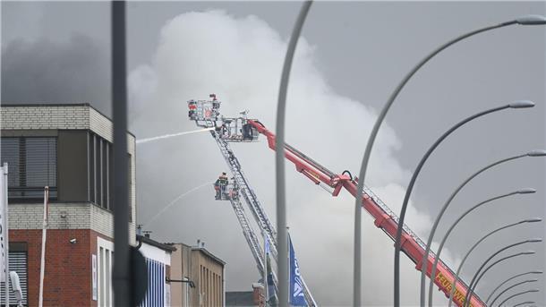 Großfeuer-Rauchwolke verdunkelt Hamburger Innenstadt Von Drehleitern aus spritzen Feuerwehrleute Wasser auf brennende und stark rauchende Lagerhallen.