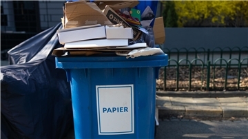 Eine Abfalltonne ist prall gefüllt mit Papier.