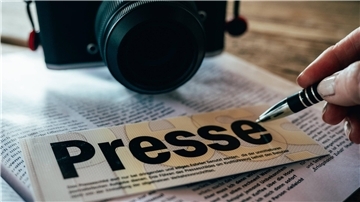 Eine  Kamera und ein Presseschild