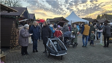 Weihnachtlich geschmückter Marktplatz mit Buden, Hütten und Menschen jeden Alters.