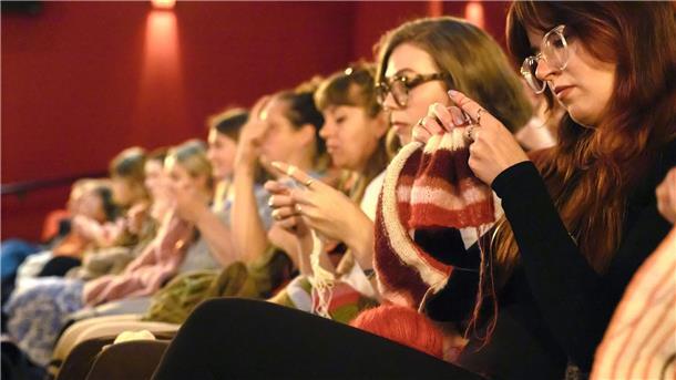 Im Strickkino bleibt das Licht an Vorn läuft der Film „Köln 75“, in den Reihen wird gestrickt.