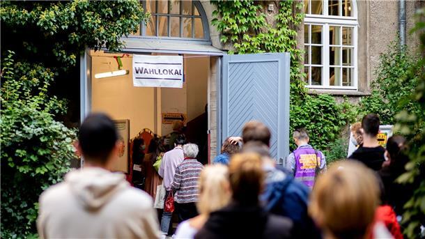 Wählerinnen und Wähler warten im Stadtteil Prenzlauer Berg in einer langen Schlange vor einem Wahllokal.