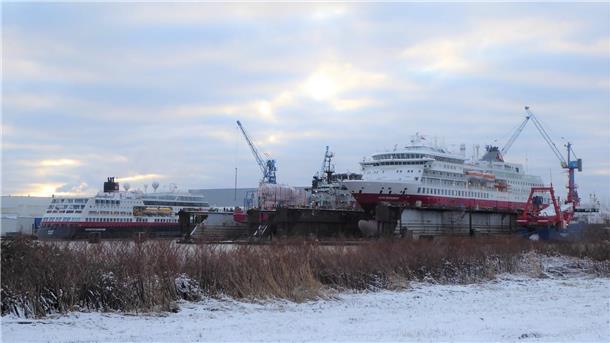 Ein Expeditionskreuzfahrtschiff liegt im Schwimmdock, ein weiteres liegt daneben an der Pier.