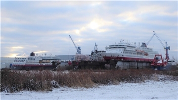 Ein Expeditionskreuzfahrtschiff liegt im Schwimmdock, ein weiteres liegt daneben an der Pier.