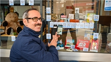 Ware sehen, QR-Code scannen und online kaufen: So funktioniert ein Allgemeinladen. Hinter der Idee steckt die Hochschule Bremerhaven. Das Foto zeigt Projektleiter Professor Benjamin Wagner-vom-Berg vor einem Allgemeinladen in Bremerhaven.