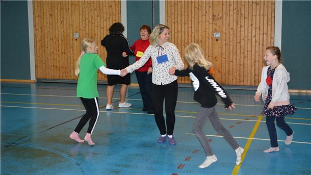 Kinder tanzen in einer Turnhalle.