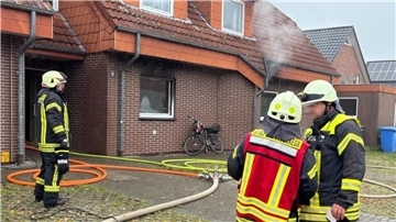 Eine Einsatzkraft der Feuerwehr steht neben einem Einsatzfahrzeug der Feuerwehr.