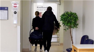 Bild einer jungen Familie auf dem Weg in den Kreißsaal eines Krankenhauses