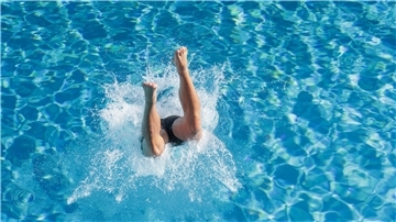 Ein Mensch springt in einem Freibad ins Wasser. Wenn es heiß wird, dann hilft unter anderem: ab ins Wasser!