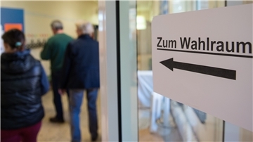 Menschen stehen in einem Wahllokal.