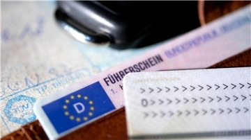 Ein Führerschein, ein Autoschlüssel, ein Personalausweis und eine Zulassungsbescheinigung liegen auf einem Portemonnaie.