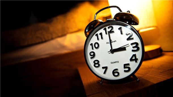  Eine Uhr steht neben einem Bett. 