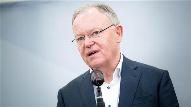 Mann mit Brille und Sakko steht an einem Mikrofon.
