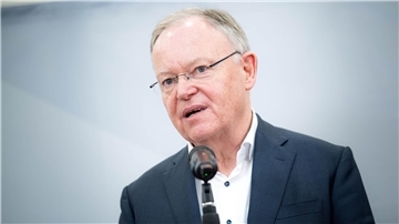 Mann mit Brille und Sakko steht an einem Mikrofon.