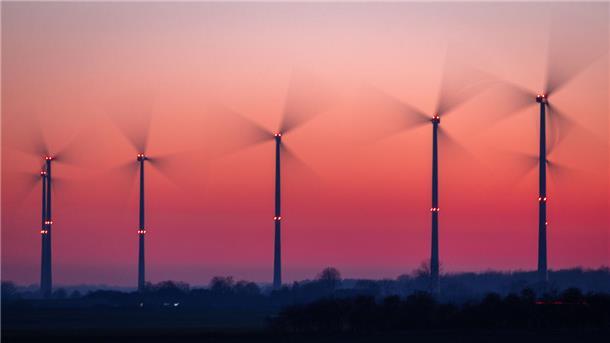 Die Rotoren von Windkraftanlagen drehen sich nach Sonnenuntergang.