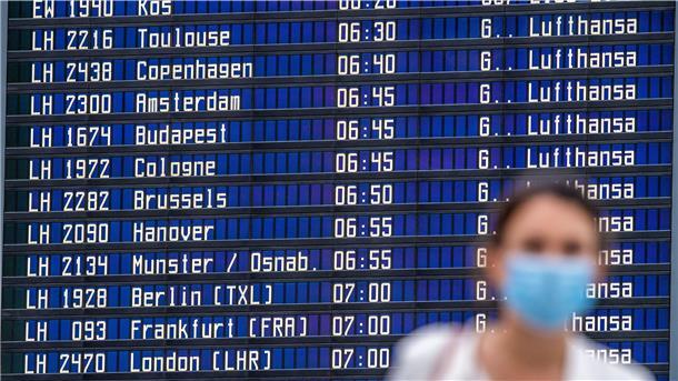 Eine Frau steht vor einer Anzeigetafel im Flughafen. 