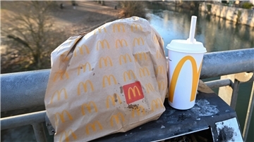 Eine McDonald's To-Go-Tüte und ein To-Go-Becher stehen auf einem Mülleimer auf der Neckarbrücke in Tübingen (gestellte Szene).