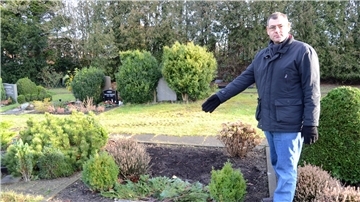 Ein Manns steht auf einem Friedhof. Der Grabstein wurde gestohlen.