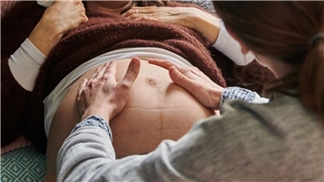 Bild von einer Hebamme, die eine schwangere Frau untersucht