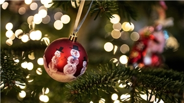 Eine Weihnachtskugel hängt an einem Weihnachtsbaum mit einer Lichterkette. Weihnachten, das Fest der Familie und der Liebe - doch mancher bleibt an Heiligabend einsam und gerät aus anderen Gründen in eine Krise. +++ dpa-Bildfunk +++