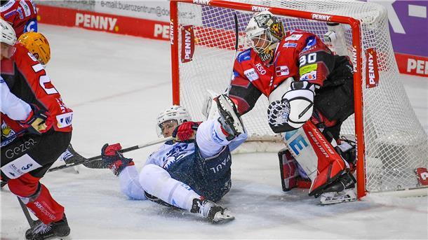 Ein Eishockeytorwart steht im Tor. Davor liegt ein Spieler.