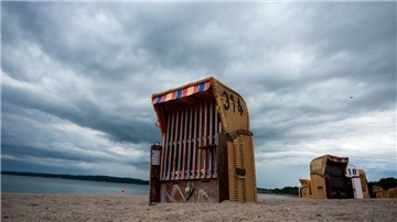 Strandkörbe unter einem wolkenverhangenen Himmel.