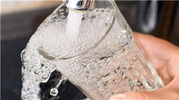 Aus dem Wasserhahn wird ein Glas befüllt. 