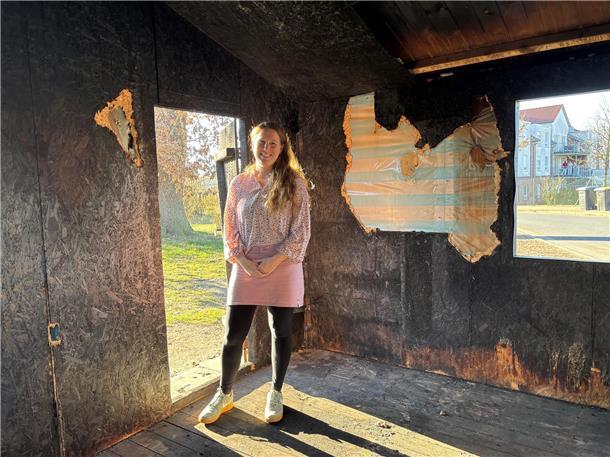 Eine Frau steht in einer Holzhütte. Seit einem Brand ist das Tarmstedter Tauschhaus eine Ruine.