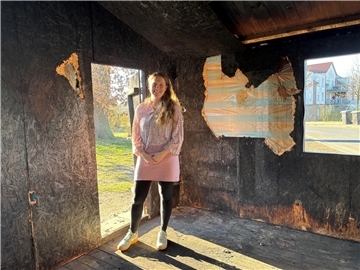Eine Frau steht in einer Holzhütte. Seit einem Brand ist das Tarmstedter Tauschhaus eine Ruine.