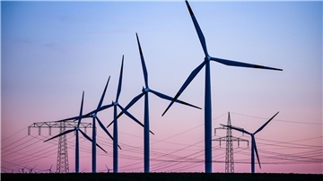 Windkraftanlagen und Hochspannungsleitungen sind vor dem Abendhimmel bei Leuna zu sehen.