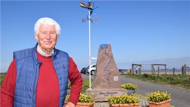 Ein älterer Mann steht neben dem Weserstein in Nordenham-Blexen.