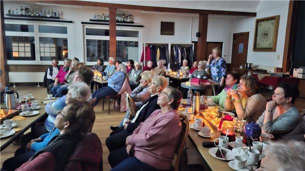 Frauen sitzen in einem Saal und lauschen einem Vortrag.
