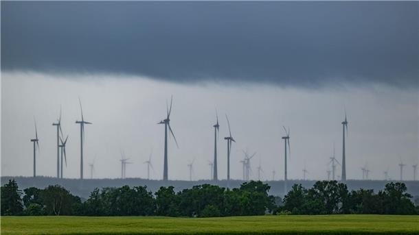  Dunkle Wolken und Regen ziehen über einen Windpark