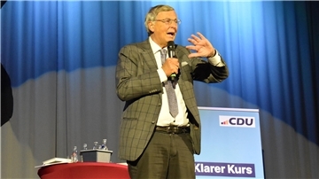 Mann mit Mikrofon vor Vorhang