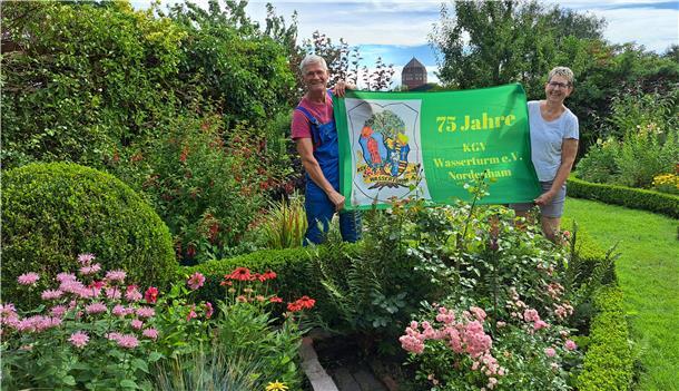 Bild von Wolfgang Engels, Vorsitzender des Kleingartenvereins Wasserturm in Nordenham, und seiner Frau Jutta mit einem Banner zum 75-jährigen Bestehen des Vereins.