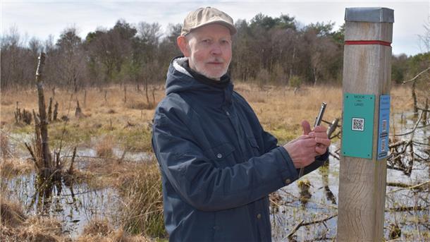 Wolfgang Marten lädt mit seinem Smartphon einen QR-Code an einer Stehle im Torfweg, hinter dem sich Gedichte und Geschichten verbergen. 