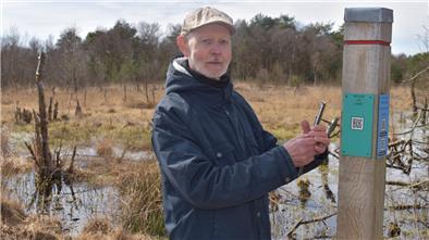 Wolfgang Marten lädt mit seinem Smartphon einen QR-Code an einer Stehle im Torfweg, hinter dem sich Gedichte und Geschichten verbergen. 