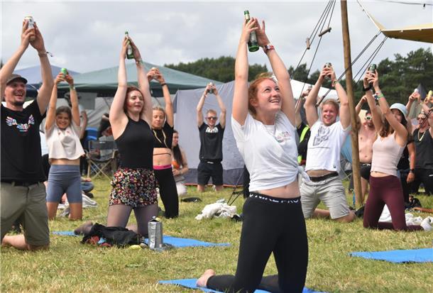 Menschen auf dem Deichbrand-Festival, die Bier-Yoga machen. 