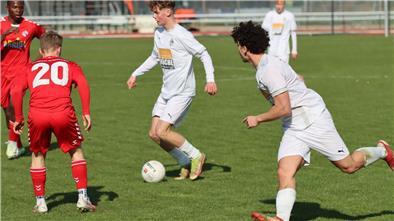 Regionalliga-Saison endet mit einer Niederlage für U19 des JFV AOBHH Zwei junge Männer in weißen Trikots laufen hinter einem Ball her, zwei junge Männer in roten Trikots stellen sich in den Weg.