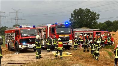 Feuerwehrleute und -fahrzeuge stehen auf einem Gelände