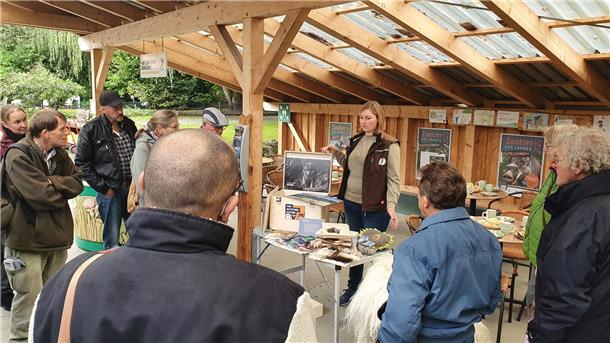 Leute hören einer Frau am Info-Stand zu