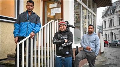 Drei Männer vor einem Haus
