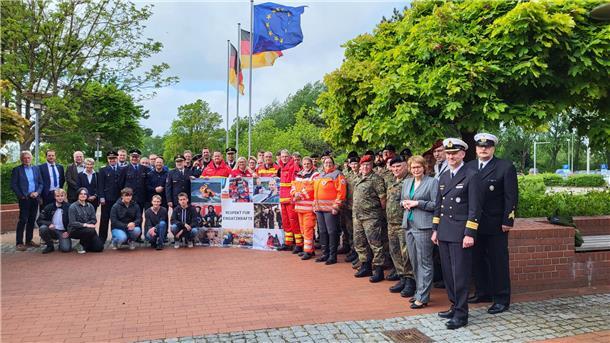 Einsatzkräfte, Politiker, stellen sich zum Gruppenfoto auf.